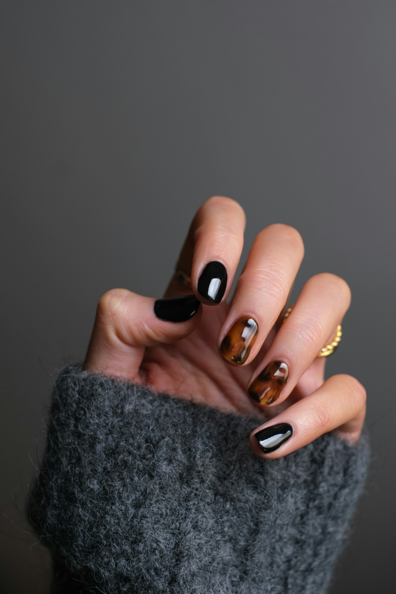 Close view of a glossy tortoiseshell and black gel manicure