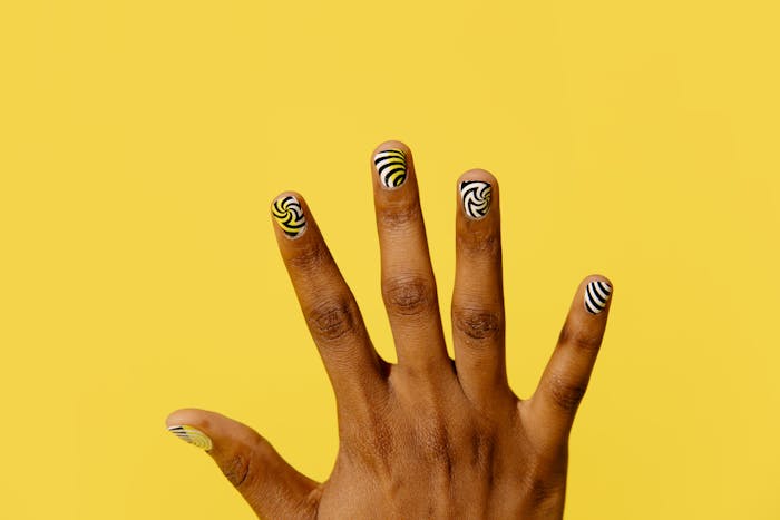 Graphic gold, black, and white swirl nail art